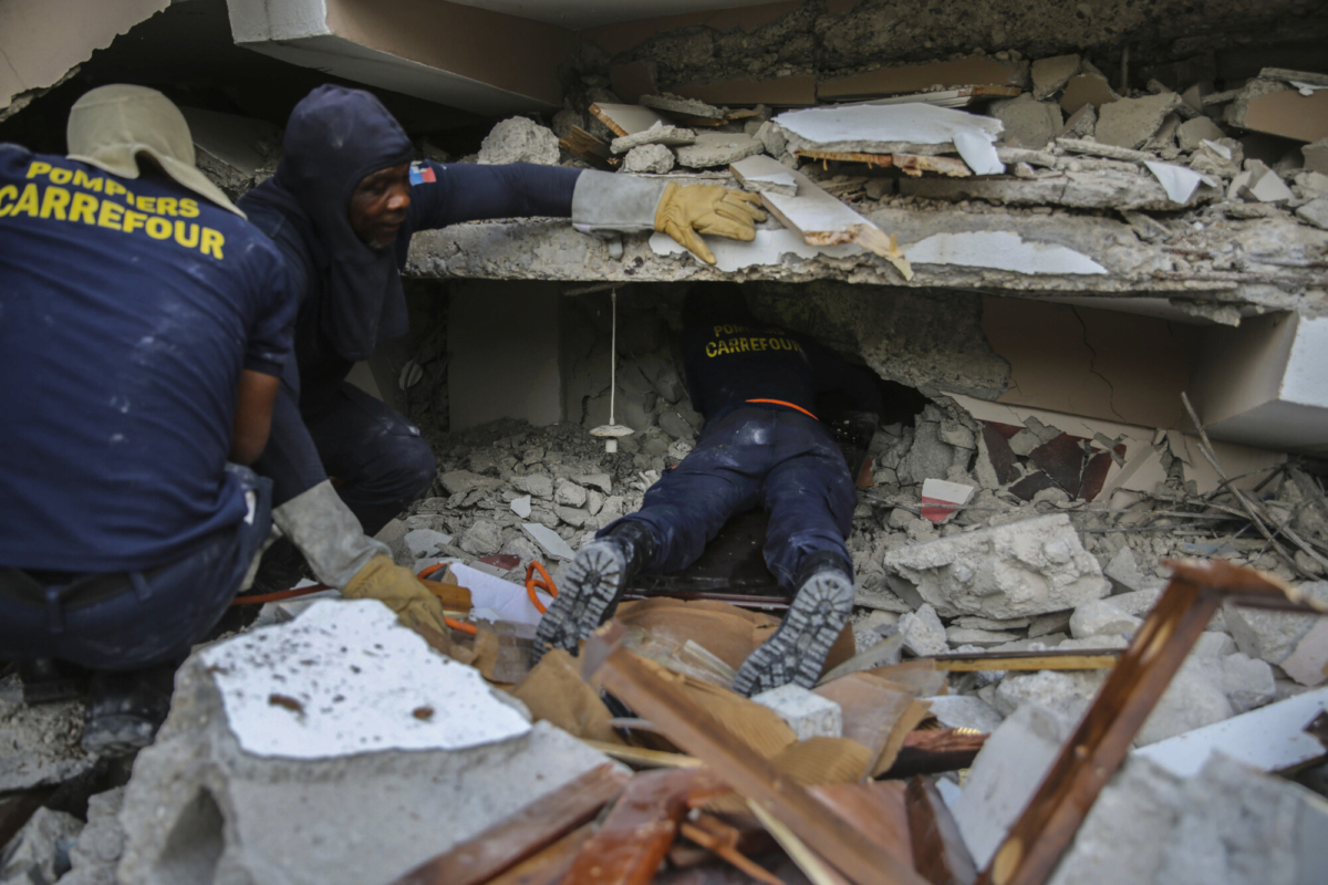Firefighters search for survivors inside a collapsed building, after Saturday's 7.2 magnitude earthquake in Les Cayes, Haiti, on Aug. 15, 2021. (Joseph Odelyn/AP Photo)