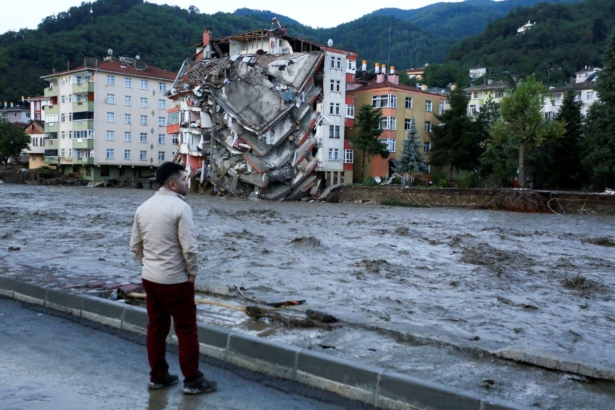 A man looks on as floodwaters sweep by in Bozkurt town of Kastamonu Province of Turkey, on Aug. 12, 2021. (IHA via AP)