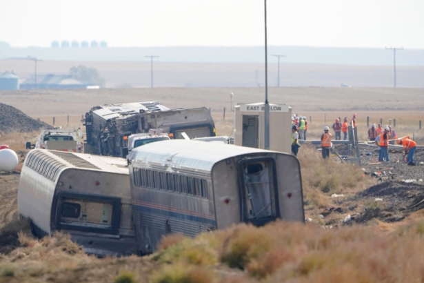 Workers stand near train tracks next to overturned cars from an Amtrak train, near Joplin, Mont., on Sept. 27, 2021. (Ted S. Warren/AP Photo)