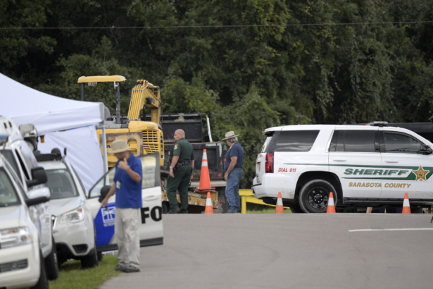 A Sarasota County Sheriff's Office deputy and a Sarasota County worker direct a truck carrying excavating equipment into the Carlton Reserve during a search for Brian Laundrie, in Venice, Fla., on Sept. 21, 2021. (Phelan M. Ebenhack/AP Photo)
