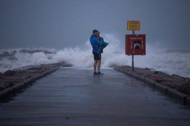 Local resident John Smith holds his 18-month-old son Owen as he stands near breaking waves on a pier ahead of the arrival of Tropical Storm Nicholas in Galveston, Texas, on Sept. 13, 2021. (Adrees Latif/Reuters)