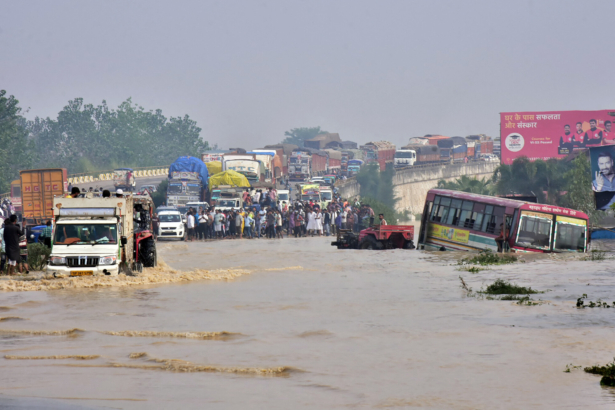 Commuters stand on a flyover on a flooded national highway after river Kosi overflowed following heavy rains near Rampur in India's Uttar Pradesh state on Oct. 20, 2021. (AFP via Getty Images)