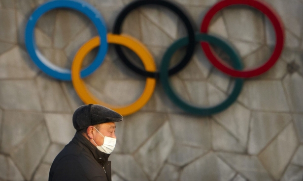 A man walks past the Olympic rings on the exterior of the National Stadium, in Beijing, on Feb. 2, 2021. (Mark Schiefelbein/AP Photo)