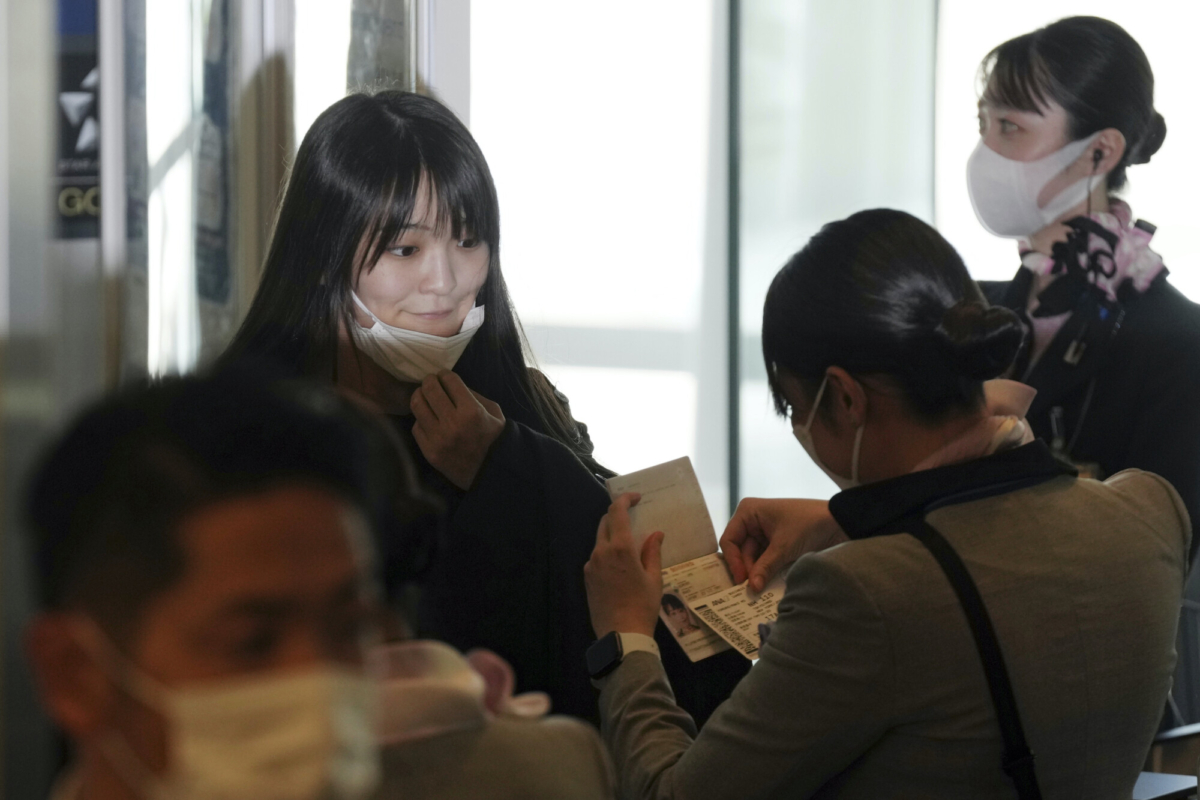 Japan's former Princess Mako (L), the elder daughter of Crown Prince Akishino, takes her mask off at a boarding gate to aboard an airplane to New York with her husband Kei Komuro (not in picture), at Tokyo International Airport, on Nov. 14, 2021. (Eugene Hoshiko/AP Photo)