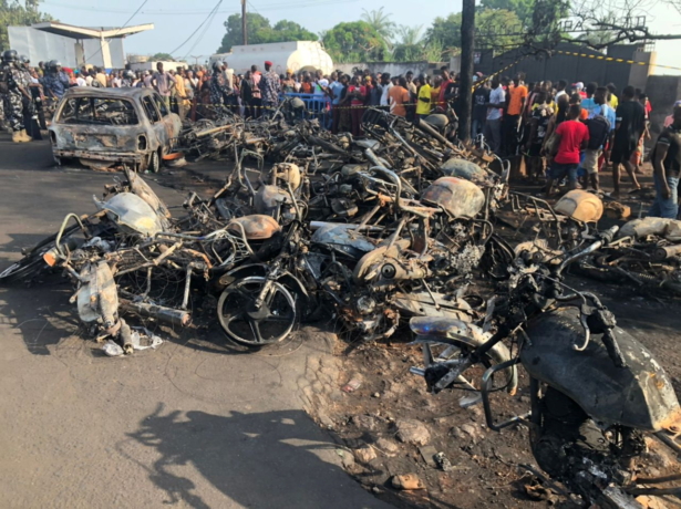 People watch burnt car and motorcycles after a fuel tanker explosion in Freetown, Sierra Leone on Nov. 6, 2021. (National Disaster Management Agency-Sierra Leone/Handout via Reuters)