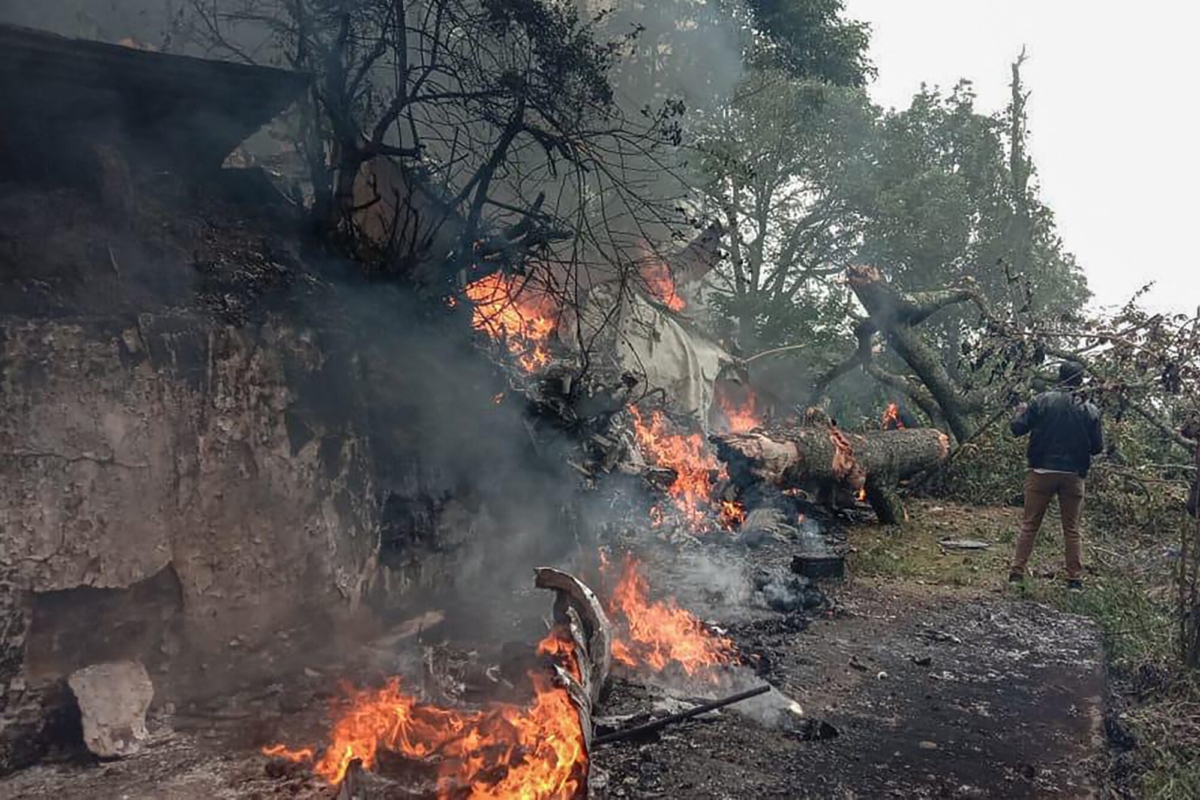 A man stands next to the burning debris of an IAF Mi-17V5 helicopter crash site in Coonoor, Tamil Nadu, on Dec. 8, 2021. (Surya Narayanan/AFP via Getty Images)