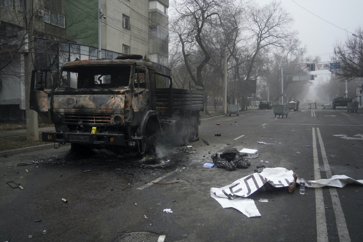 A victim's body covered by a banner (R), lays near to a military truck, which was burned after clashes, in Almaty, Kazakhstan, on Jan. 6, 2022. (Vladimir Tretyakov/NUR.KZ via AP)