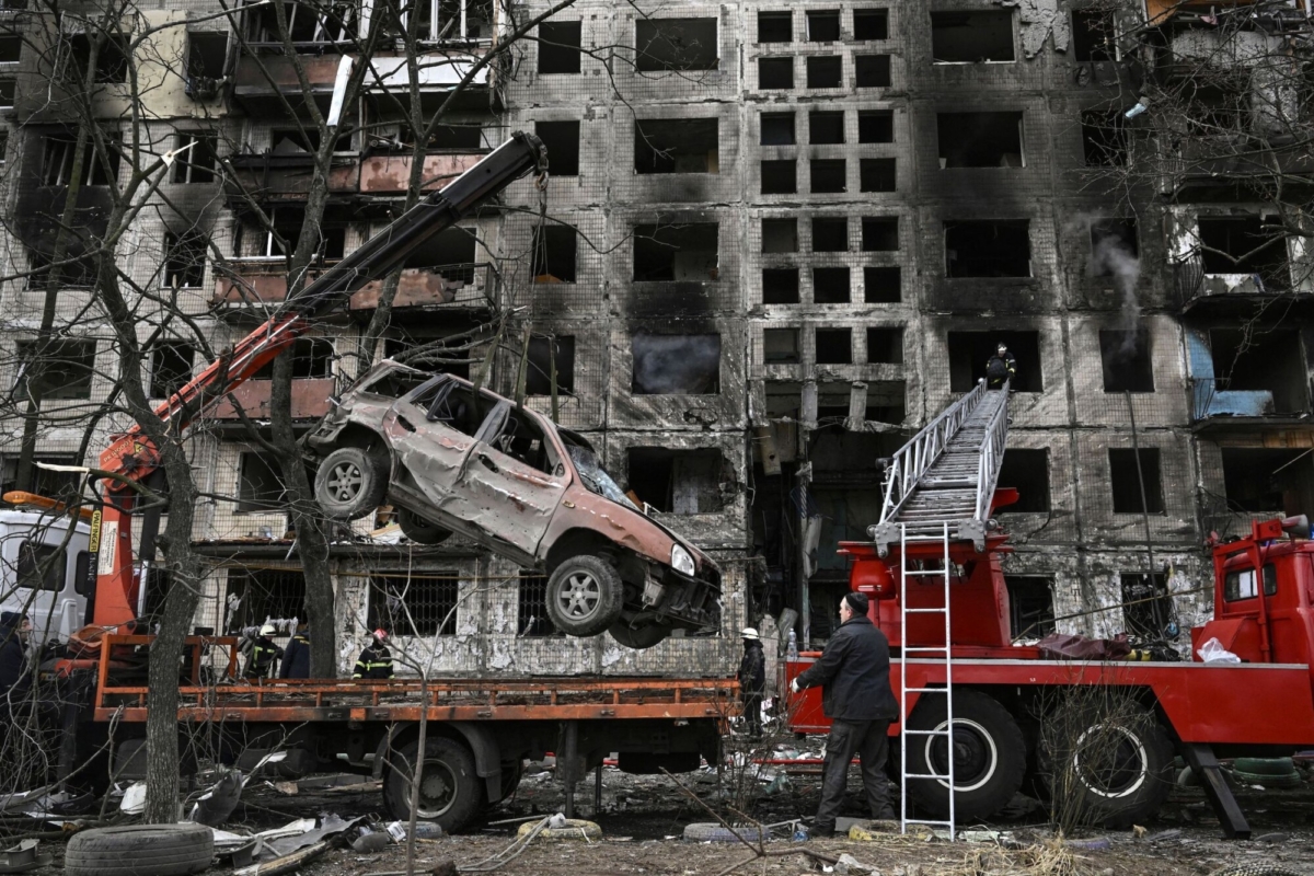 A crane removes a ruined car from in front of a destroyed apartment building after it was shelled in the northwestern Obolon district of Kyiv on March 14, 2022. (Aris Messinis/AFP via Getty Images)