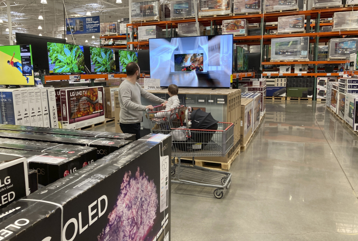 A shopper pushes a child in a cart while browsing big-screen televisions on display in the electronics section of a Costco warehouse in Lone Tree, Colo., on March 29, 2022. (David Zalubowski/AP Photo)