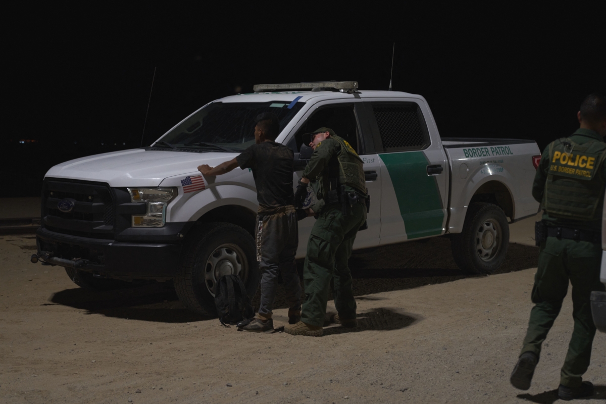A Border Patrol officer frisks a man after he illegally crossed the U.S.–Mexico border in Yuma, Ariz., on July 11, 2022. (Allison Dinner/AFP via Getty Images)