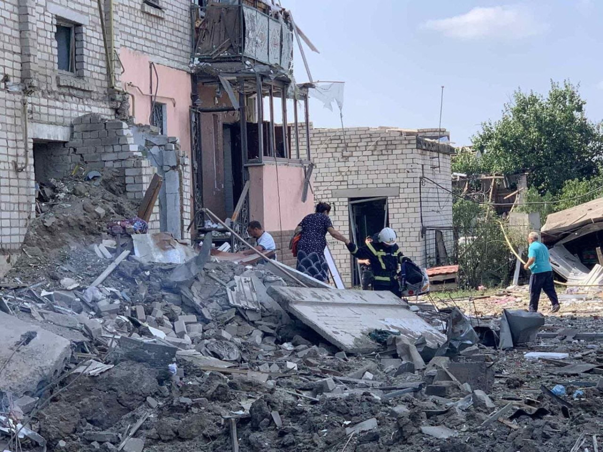 A rescuer helps a woman to be evacuated from a residential building damaged by a missile strike in Voznesensk, Mykolaiv region, Ukraine, on Aug. 20, 2022. (Press service of the State Emergency Service of Ukraine/Handout via Reuters)