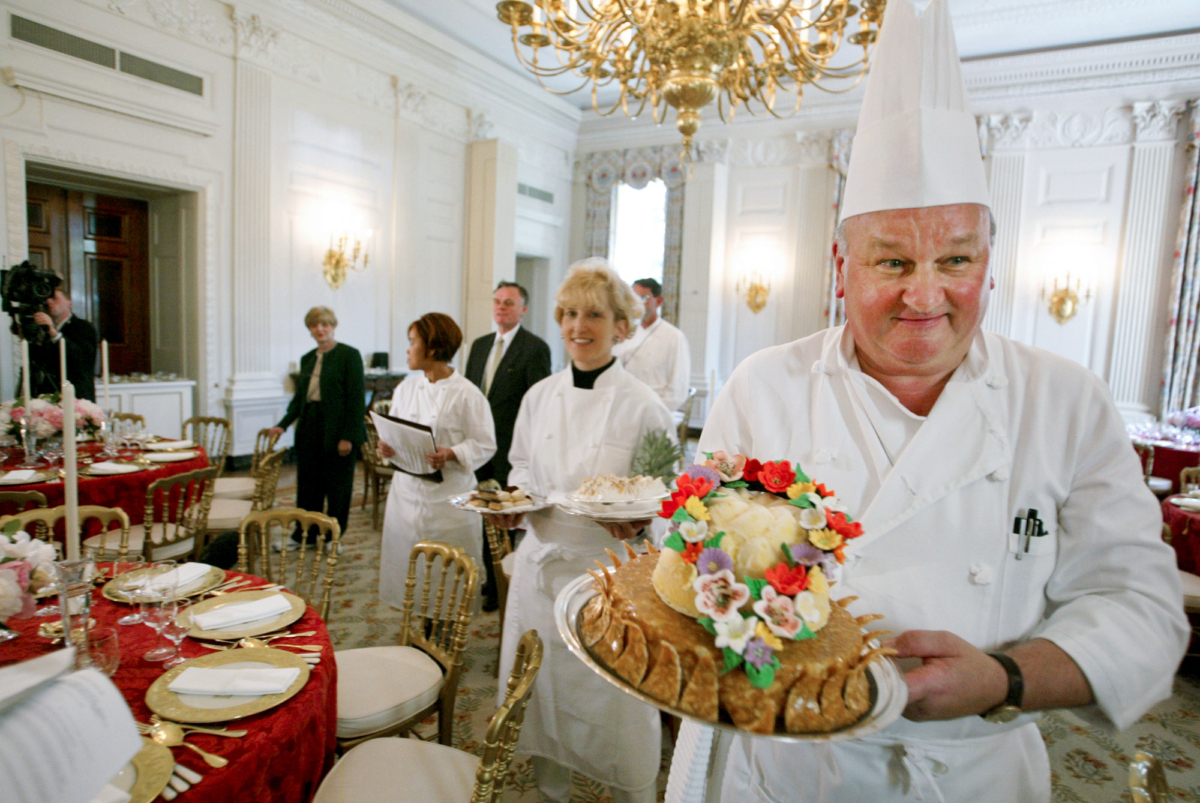 White House pastry chef Roland Mesnier (R) displays a mango coconut lei, the dessert for the dinner hosted by President George W. Bush for Philippine President Gloria Macapagal Arroyo, in the State Dining Room in the White House on May 19, 2003. (Charles Dharapak/AP Photo)