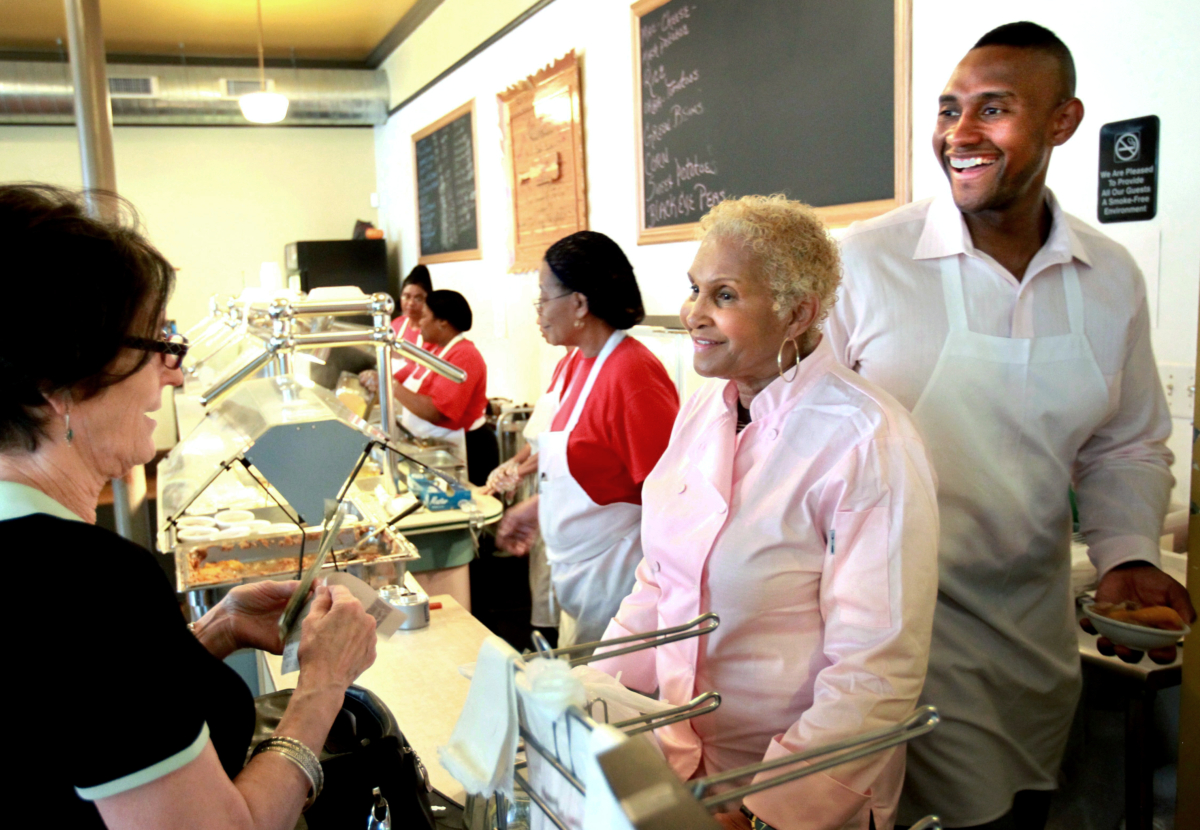 A customer picks up food from Sweetie Pie's owner Robbie Montgomery (2nd R) and Montgomery's son James "Tim" Norman (R) at the shop in St. Louis on April 19, 2011. (David Carson/St. Louis Post-Dispatch via AP)