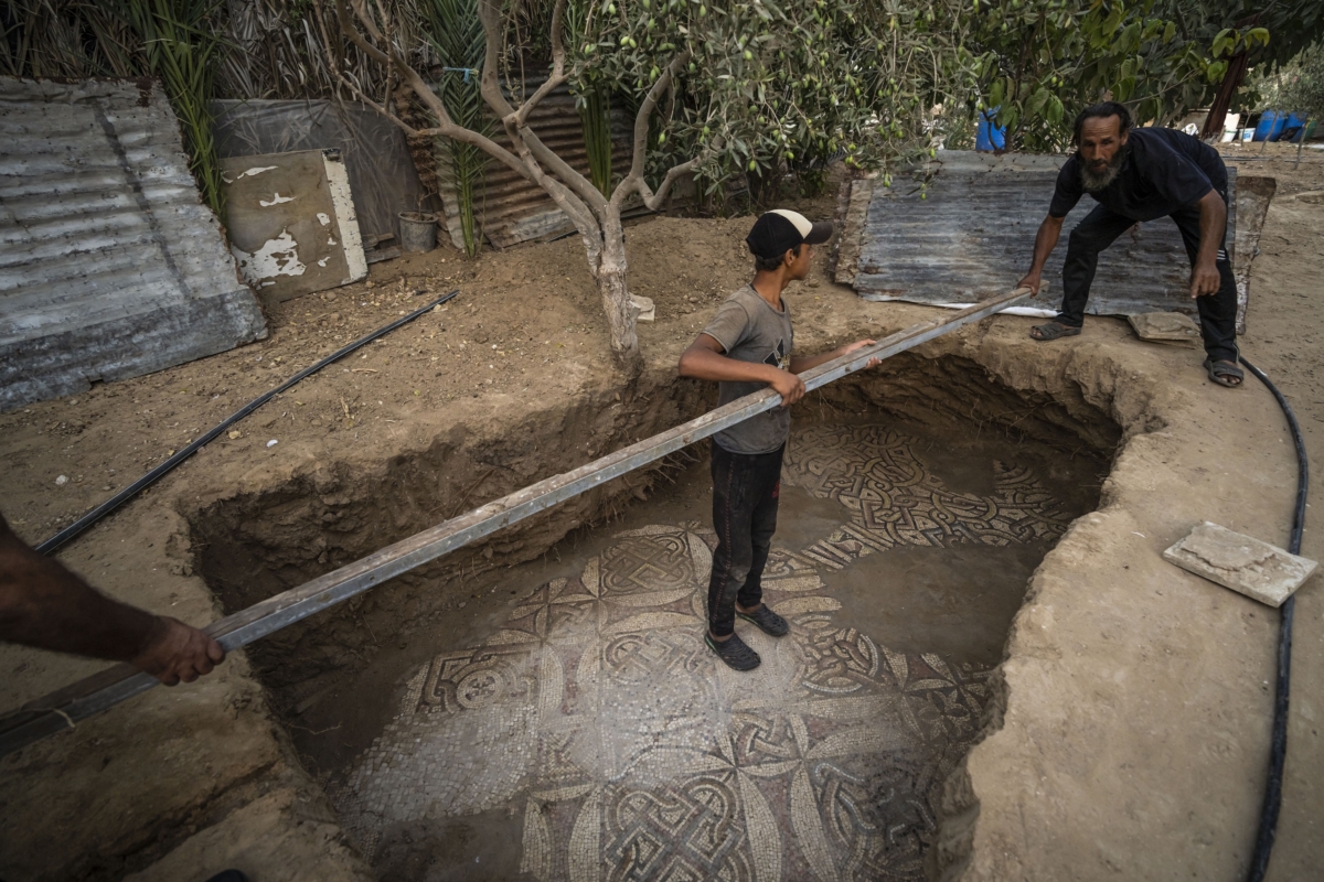 Palestinians clean around a Byzantine-era mosaic floor that was uncovered recently by a farmer in Bureij in central Gaza Strip on Sept. 5, 2022. (Fatima Shbair/AP Photo)