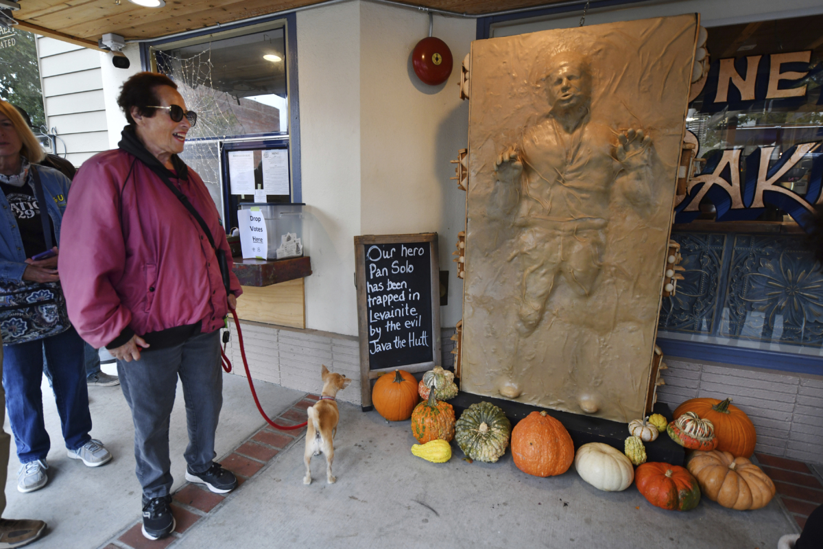Sandy Alvord waits in line as her dog Charlie glances up at a sculpture of "Star Wars" character Han Solo frozen in carbonite and made entirely of bread while at the One House Bakery in Benicia, Calif., on Oct. 16, 2022. (Jose Carlos Fajardo/Bay Area News Group via AP)