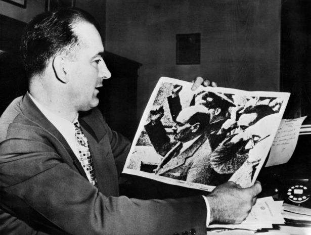 US Senator Joseph McCarthy holds a picture showing