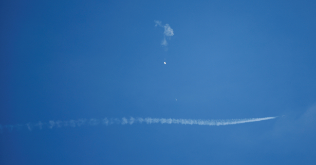 A jet flies by a Chinese spy balloon
