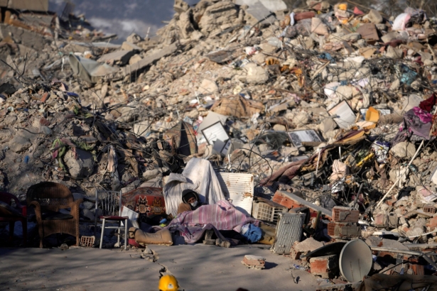 A man sleeps in front of a destroyed building in Kahramanmaras, southeastern Turkey, on Feb. 13, 2023. (Khalil Hamra/AP Photo)