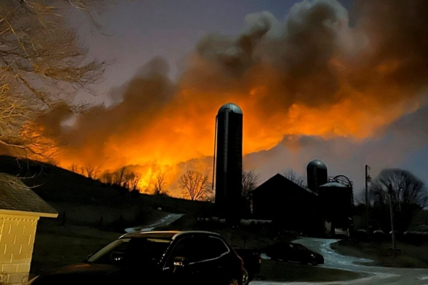 A train fire is seen from a farm