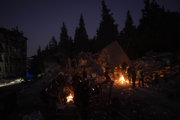 Friends and relatives of the Daghli family gather around bonfires while rescue teams search for family members under the rubble of a destroyed building in Antakya, southeastern Turkey, on Feb. 15, 2023. (Bernat Armangue/AP Photo)