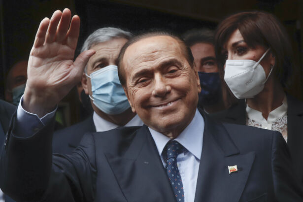 Former Italian Premier Silvio Berlusconi waves to reporters as he arrives at the Chamber of Deputies to meet Mario Draghi, in Rome, on Feb. 9, 2021. (Alessandra Tarantino/AP Photo)
