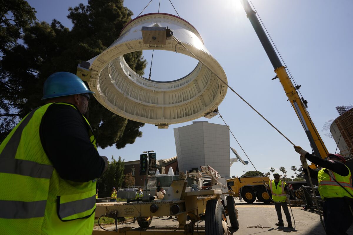 Workers used a crane to hoist the Solid Rocket Aft Skirts, the bottom segments of the boosters of the Space Shuttle Endeavour, before placing them on top of a seismic isolator pad inside the Shuttle Gallery at the Samuel Oschin Air and Space Center in Los Angeles on July 20, 2023. (Damian Dovarganes/AP Photo)