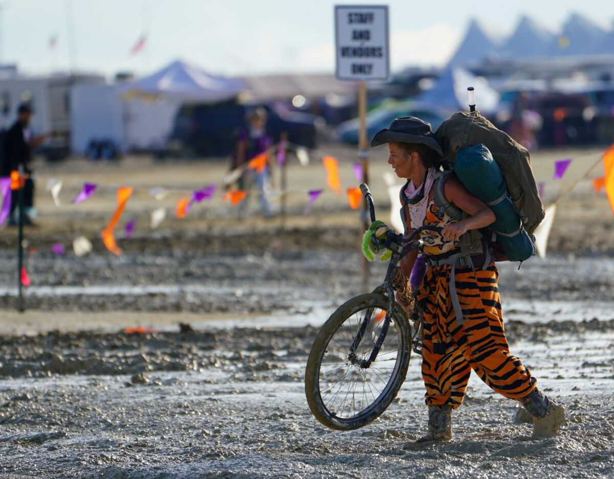 A Participant Walks Their Bike Through The Mud Near The Exit At Burning Man