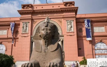 Visitors walk behind a granite sphinx in the likeness of the ancient Egyptian Pharaoh Thutmose III (1479–1425 BC) placed outside the entrance to the Egyptian Museum in the centre of Egypt's capital Cairo on Oct.  11, 2022. (Amir Makar/AFP via Getty Images)