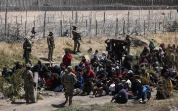Migrants of different nationalities pray in front of anti-riot agents of the Texas National Guard who prevent passage toward their border line, as seen from Ciudad Juarez, state of Chihuahua, Mexico, on April 16, 2024. (Herika Martinez / AFP via Getty Images)
