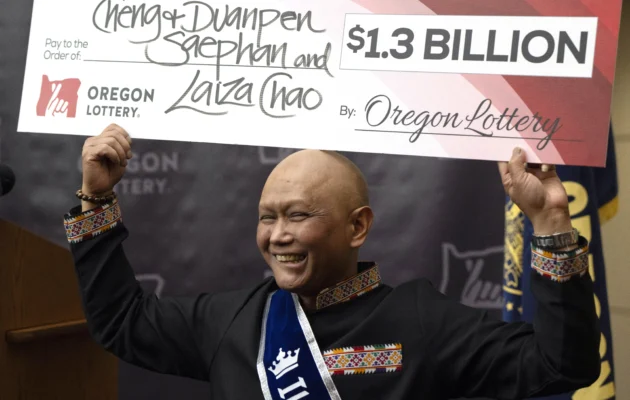 Cheng "Charlie" Saephan holds a check above his head after speaking during a news conference where it was revealed that he was one of the winners of the $1.3 billion Powerball jackpot at the Oregon Lottery headquarters in Salem, Ore., on April 29, 2024. (Jenny Kane/AP Photo)