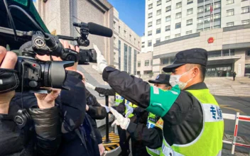 A policeman covers a camera to stop journalists from recording footage outside the Shanghai Pudong New District People's Court, where Chinese citizen journalist Zhang Zhan is set for trial in Shanghai on Dec. 28, 2020. (Leo Ramirez/AFP via Getty Images)