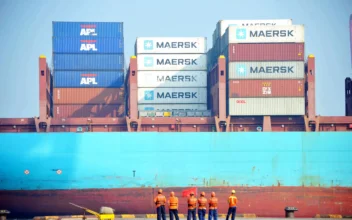 Chinese workers look as a cargo ship is loaded at a port in Qingdao, eastern China's Shandong province on July 13, 2017. (STR/AFP via Getty Images)