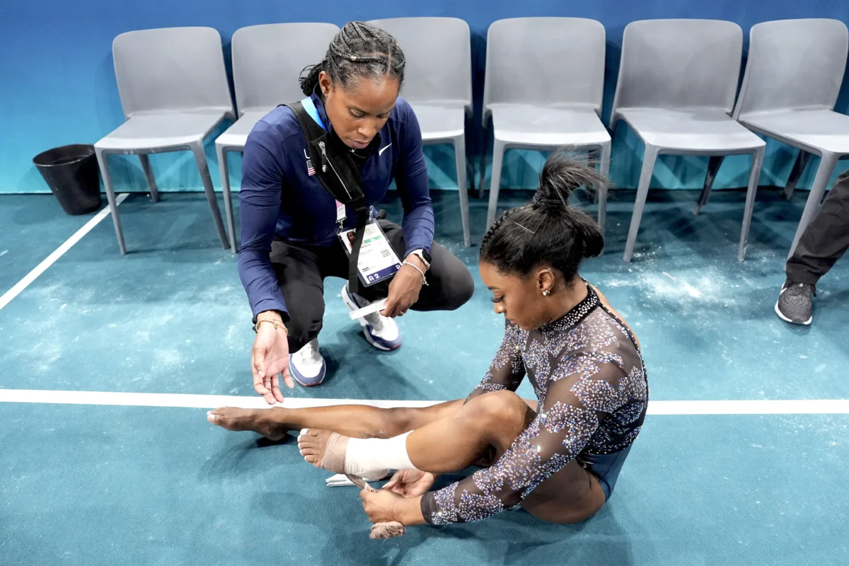 Simone Biles of the United States has her ankle taped after competing on the uneven bars during a women's artistic gymnastics qualification round at Bercy Arena at the 2024 Summer Olympics in Paris, France, on July 28, 2024. (Charlie Riedel/AP Photo)