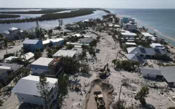 Charlotte County workers clear feet of sand from the main road on southern Manasota Key, in Englewood, Fla., following the passage of Hurricane Milton, on Oct. 13, 2024. (Rebecca Blackwell/AP Photo)