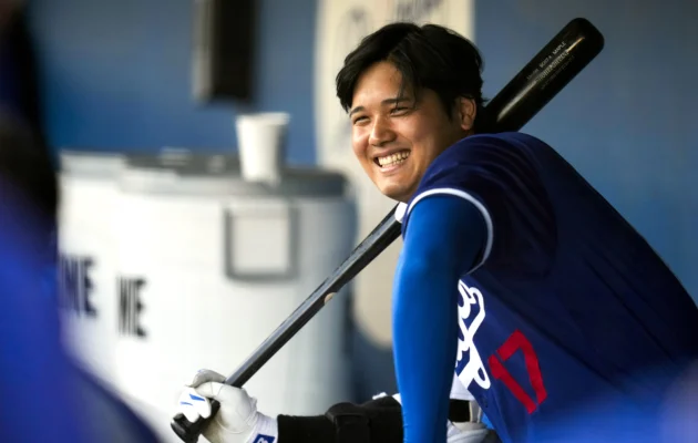 Los Angeles Dodgers designated hitter Shohei Ohtani smiles in the dugout before a spring training baseball game against the Los Angeles Angels in Phoenix on March 5, 2024. (Ashley Landis/AP Photo)