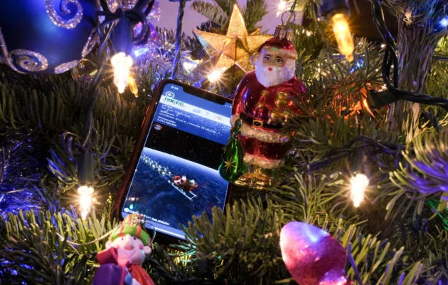 This illustration photo shows a cell phone with NORAD's Santa Tracker on screen, nestled in a Christmas tree in Los Angeles on Dec. 24, 2023. (Chris Delmas/AFP via Getty Images)