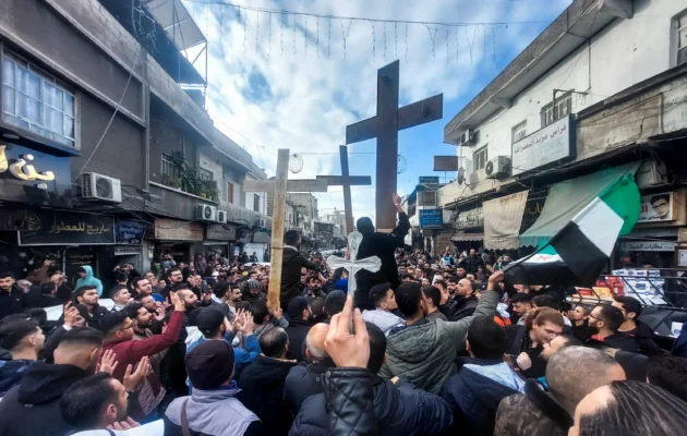 Christian Syrians lift crosses as they rally in the Duweilaah area of Damascus on December 24, 2024, to protest the burning of a Christmas tree near Hama in central Syria. Hundreds of demonstrators took to the streets in Christian areas of Damascus early on December 24, AFP journalists witnessed,  after a video spread on social media showing hooded fighters setting fire to a Christmas tree in the Christian-majority town of Suqaylabiyah near Hama in central Syria, a little more than two weeks after an armed coalition led by Islamists toppled the government of Bashar al-Assad. (Photo by Louai Beshara / AFP)