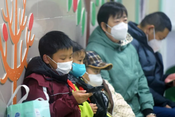 Masked children, accompanied by adults, wait to be seen by medical staff at the pediatric department of a hospital in Hangzhou, eastern China's Zhejiang Province, on Jan. 6, 2025. (STR/AFP via Getty Images)