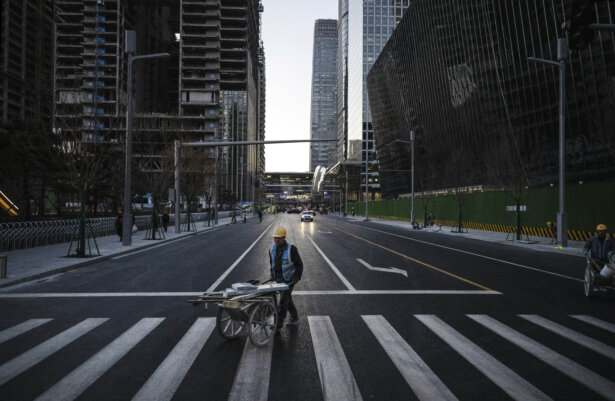 A construction worker pushes a wheelbarrow with materials across the road in the Central Business District in Beijing on Nov. 29, 2024. (Kevin Frayer/Getty Images)