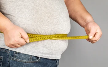 A man measures his fat belly with a measuring tape in a stock photo. (Fuss Sergey/Shutterstock)