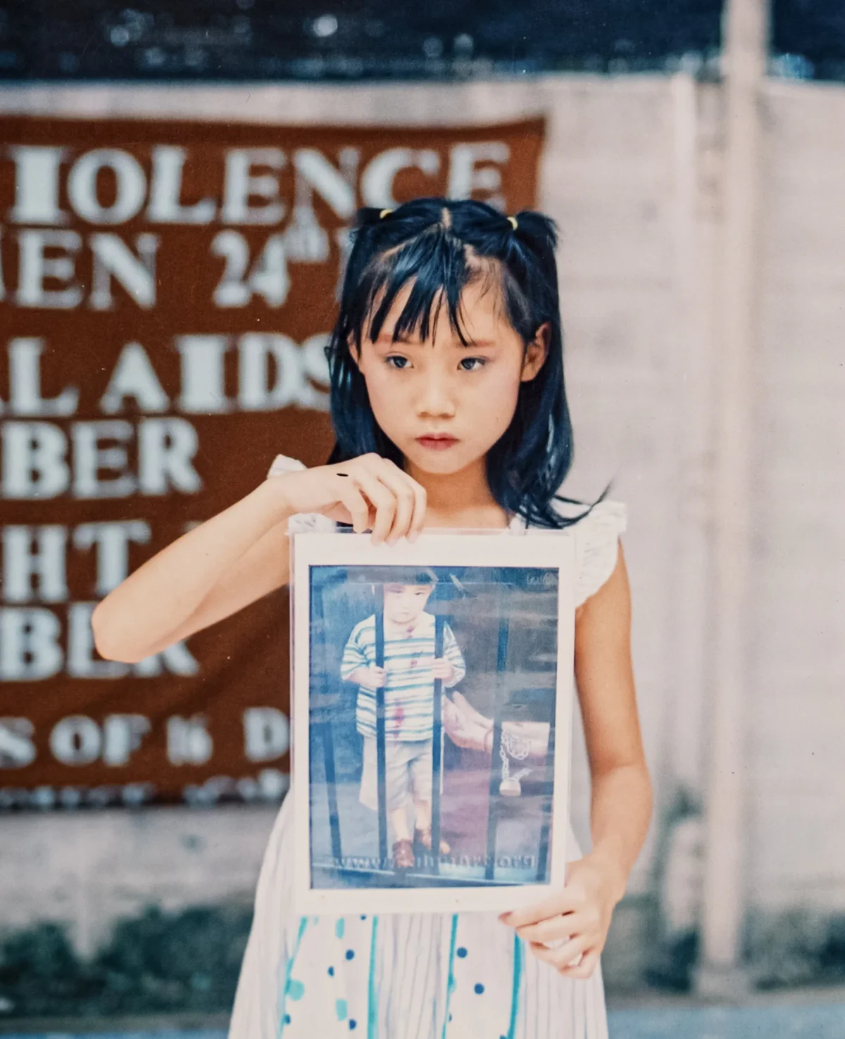 Ellie Rao holds a photo of an artwork that depicts the persecution of Falun Gong. (Samira Bouaou/The Epoch Times)