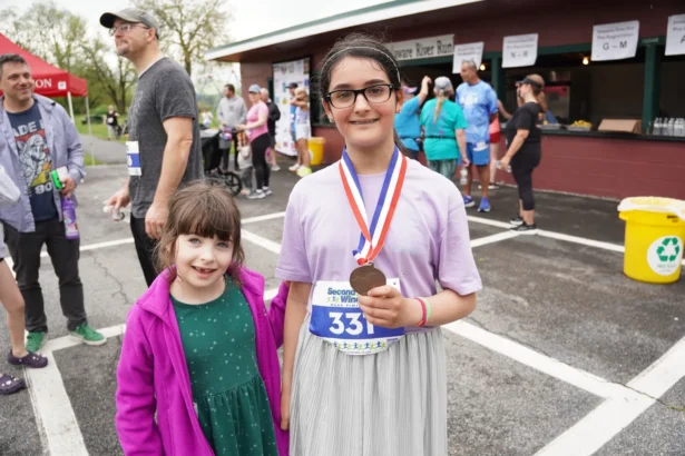 Fourth-grade student Lia Lemish (R) and her little sister Milly after Lia completed the Port Jervis Delaware River 5K Run and Walk on May 4, 2025. (Oliver Mantyk/The Epoch Times)