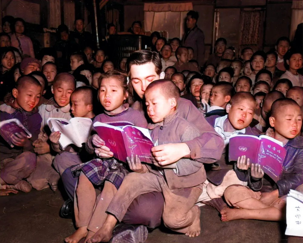 Private First Class Dave Donovan of the U.S. military sings a hymn with two Korean War orphans on his lap at an orphanage in Busan, South Korea, on Dec. 17, 1951. (Courtesy of Ahn Jae-chul, president of The World Peace Freedom United)