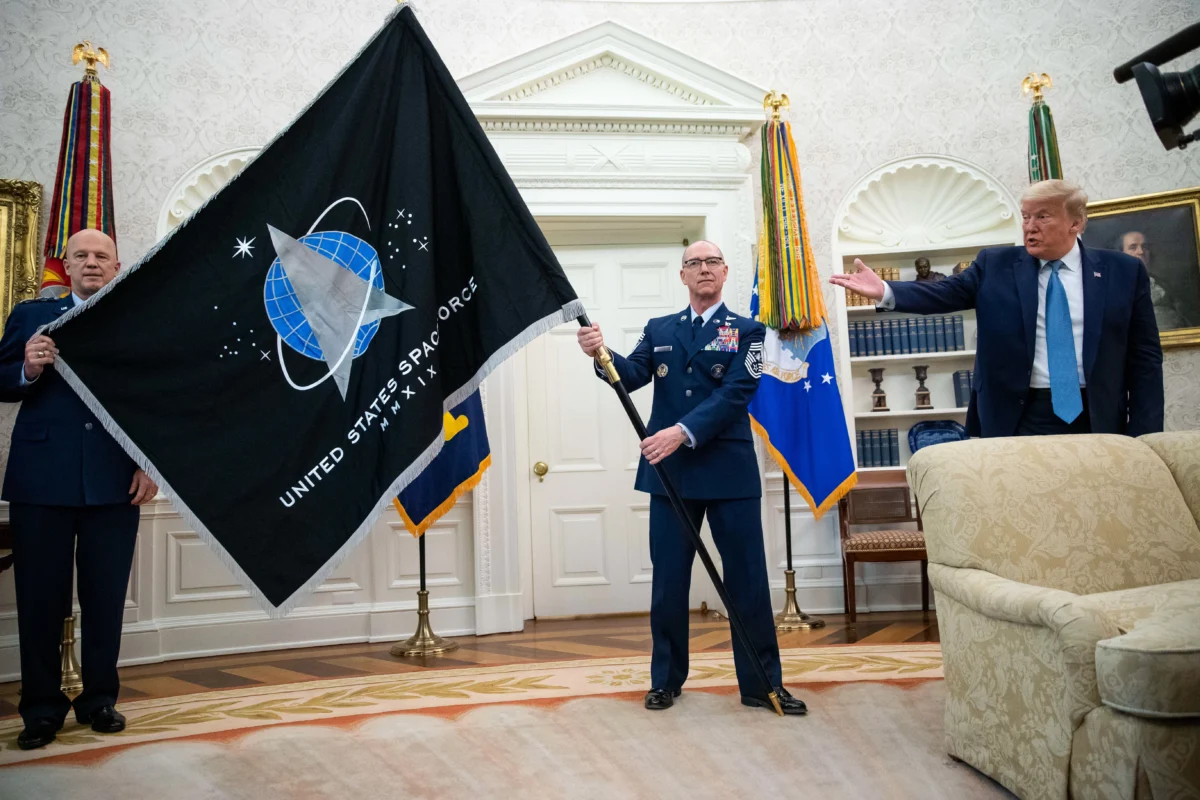 Gen. John "Jay" Raymond, Commander of U.S. Space Command (L), and Chief Master Sgt. Roger Towberman (R), hold the flag as President Donald Trump speaks during the presentation of the Space Force Flag in the Oval Office, on May 15, 2020. (Alex Brandon/AP Photo)