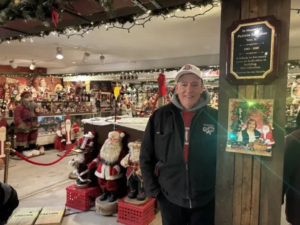 Anthony Satariano Jr. stands next to a photo of his mother, Patricia Satariano, at Clifton Mill’s Santa Claus museum in Ohio on Dec. 8, 2025. (Jeff Louderback/The Epoch Times)