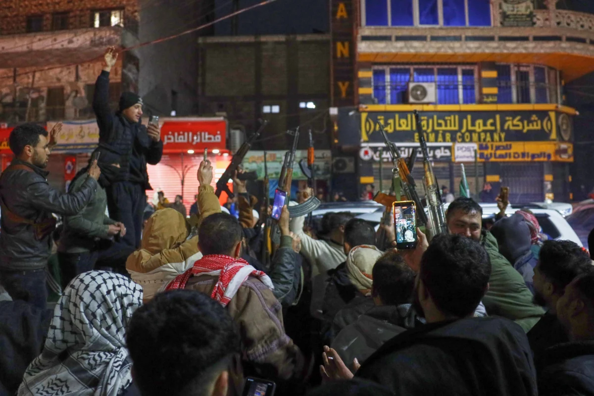 Syrian government troops and local supporters celebrate after taking control of the town from the Syrian Democratic Forces (SDF), in the Al-Naeem roundabout in the city center of Raqqa, northeastern Syria, on Jan. 18, 2026. (Omar Albam/AP Photo)