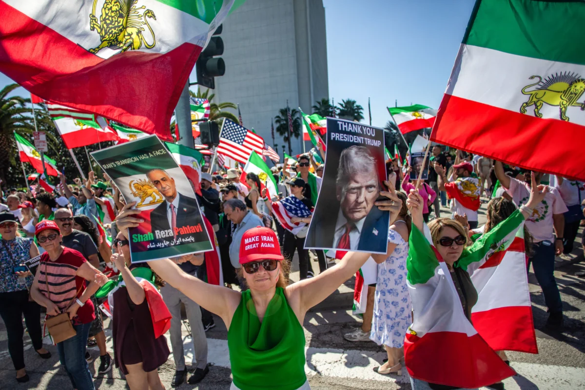 A woman holds pictures of Iranian Crown Prince Reza Pahlavi and U.S. President Donald Trump as members of the Iranian community celebrate in front of the Federal Building in Los Angeles on Feb. 28, 2026. (Apu Gomes/AFP via Getty Images)