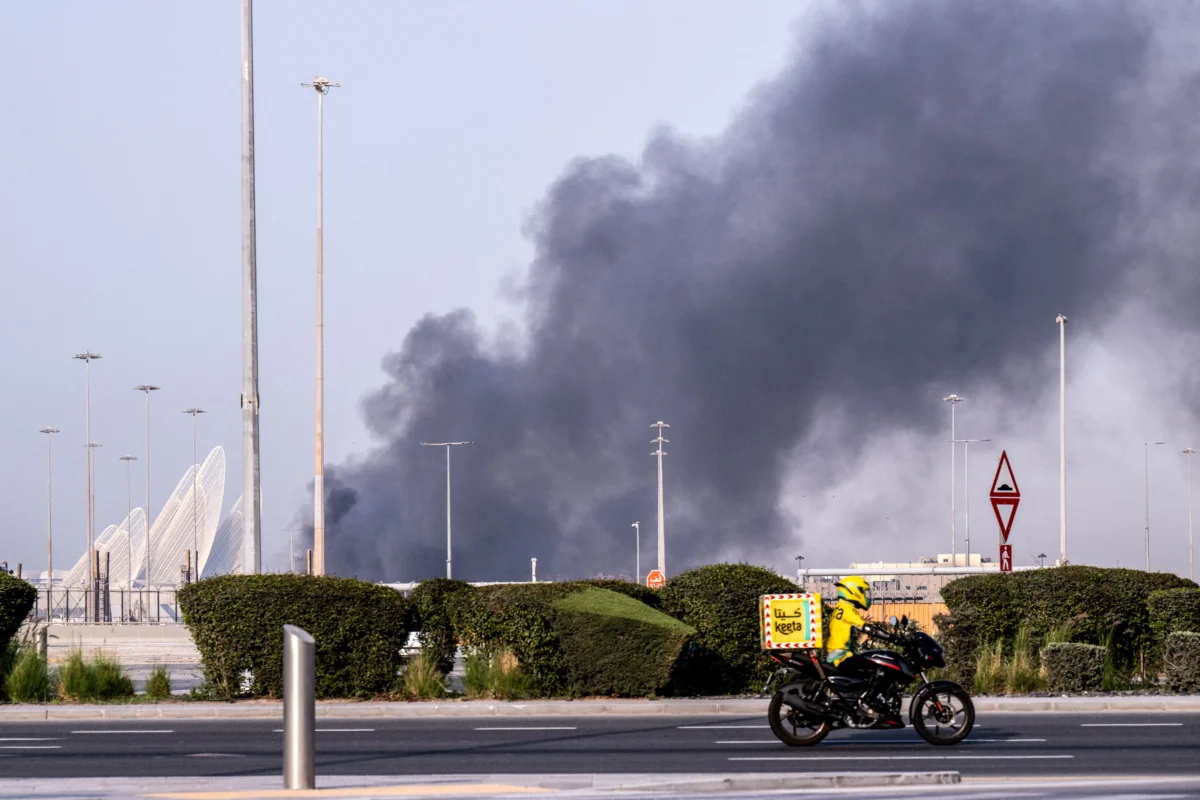 A food delivery bike drive close to a plume of smoke rising from the Zayed Port following a reported Iranian strike in Abu Dhabi, U.A.E., on March 1, 2026. (Ryan Lim/AFP via Getty Images)