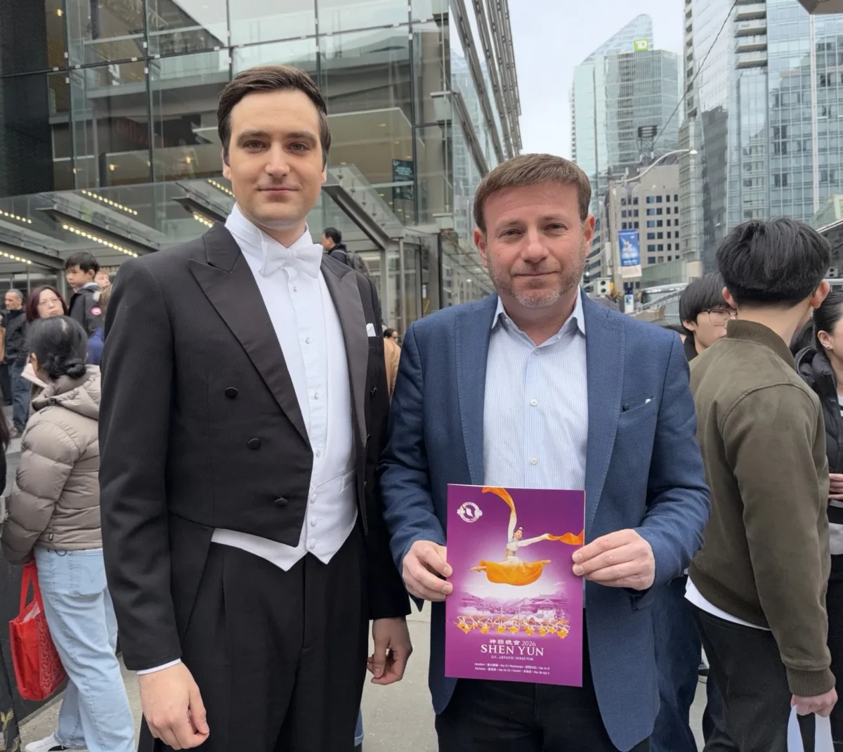 Conservative MP Roman Baber holds a Shen Yun program book while standing by one of the show’s hosts outside the Four Seasons Centre for the Performing Arts in Toronto on March 29, 2026. (The Epoch Times)