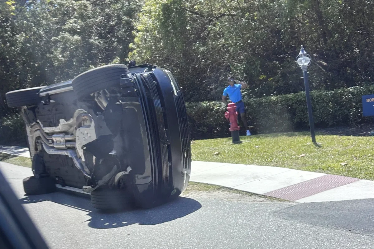 Golfer Tiger Woods stands by his overturned vehicle in Jupiter Island, Fla., on March 27, 2026. (Jason Oteri/AP Photo)